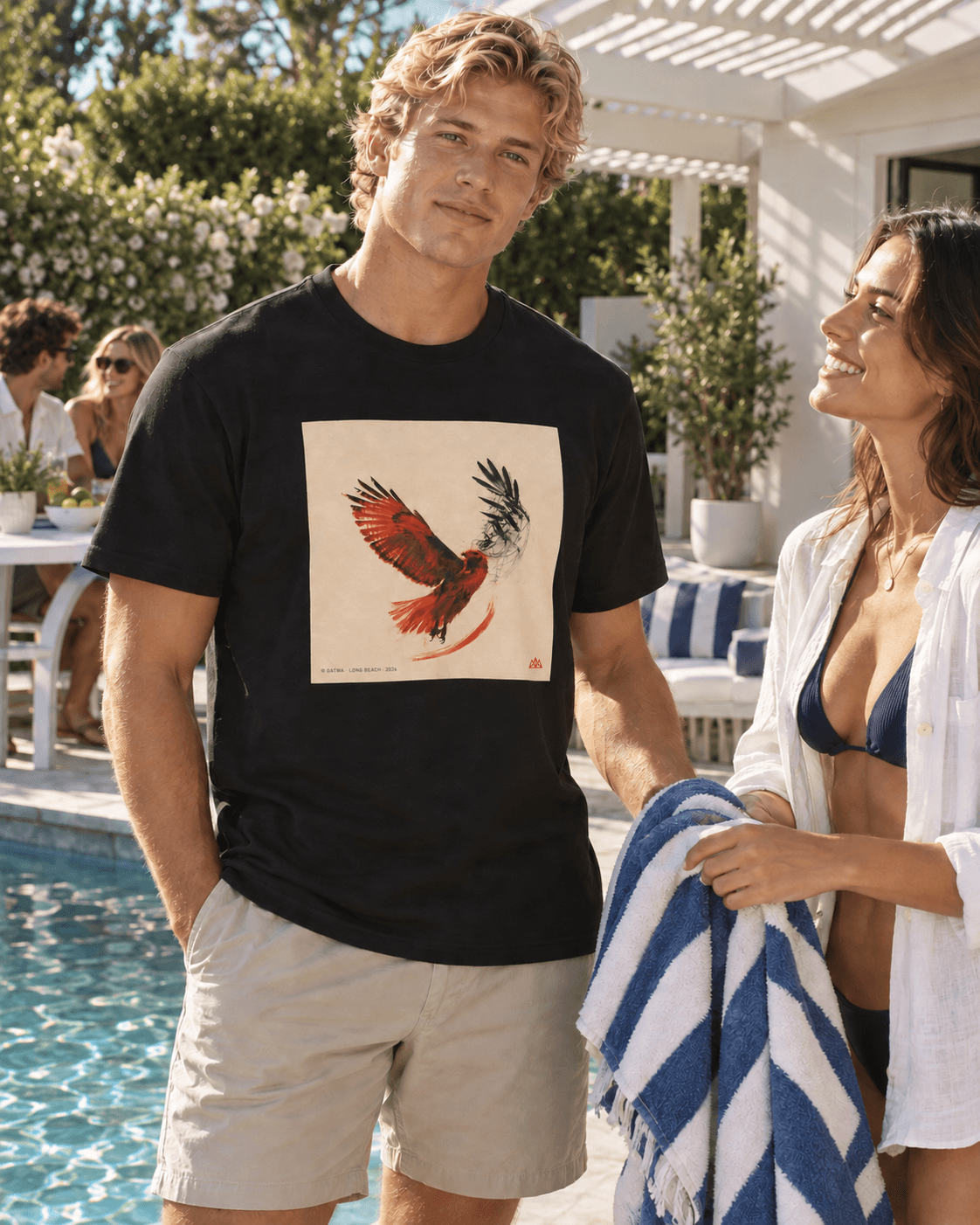 An adult man in the black THERMAL tee shares a striped towel with a woman beside a sunlit pool, with friends at the table behind